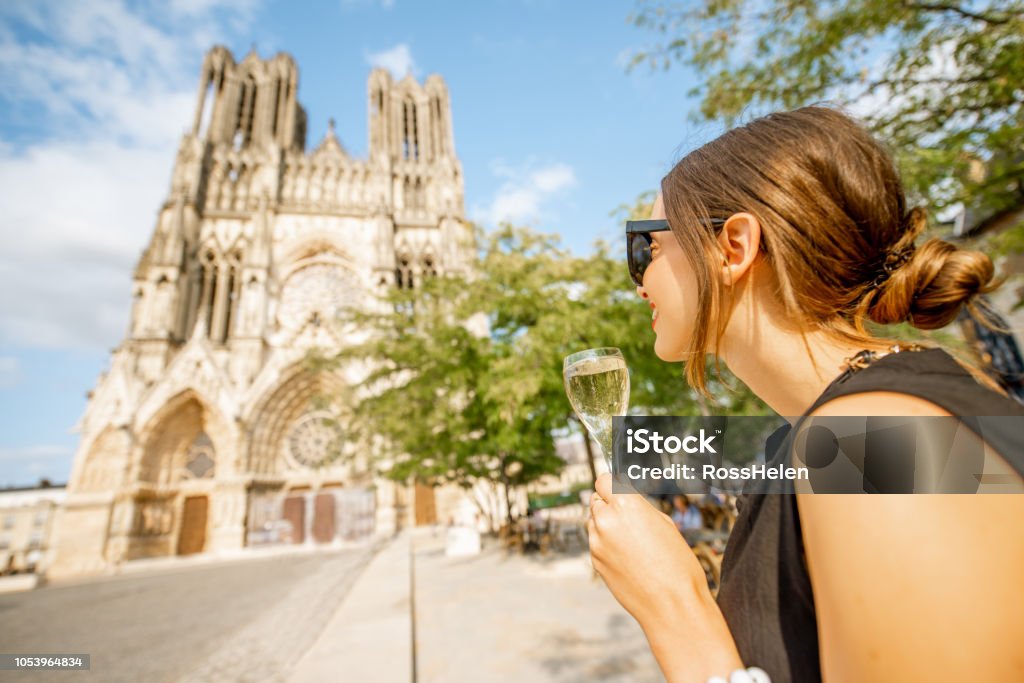 Young woman enjoying champagne standing in front of the cathedral in Reims city, capital of Champagne wine region, France