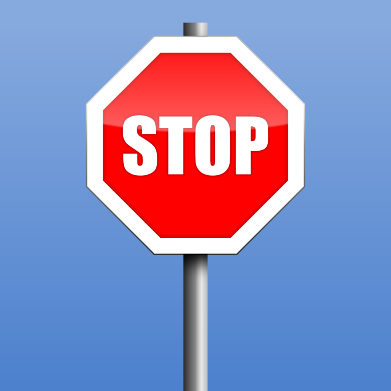 Red stop sign with bold white letters against a blue background, indicating the need to halt, commonly used in traffic control.