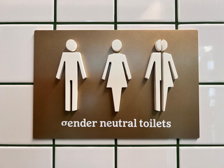 Sign indicating gender-neutral toilets, featuring male, female, and non-binary symbols. Emphasizes inclusivity in restroom accessibility.