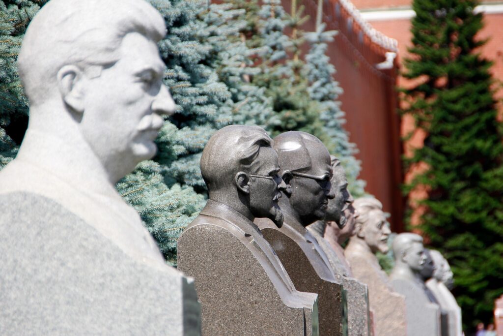 Busts of historical Soviet leaders lined up against lush greenery, highlighting significant figures in Russian history.