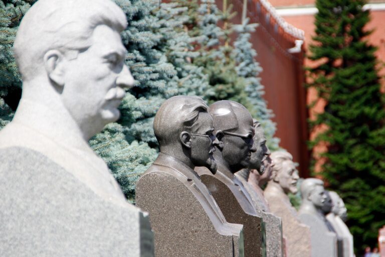 Busts of historical Soviet leaders lined up against lush greenery, highlighting significant figures in Russian history.