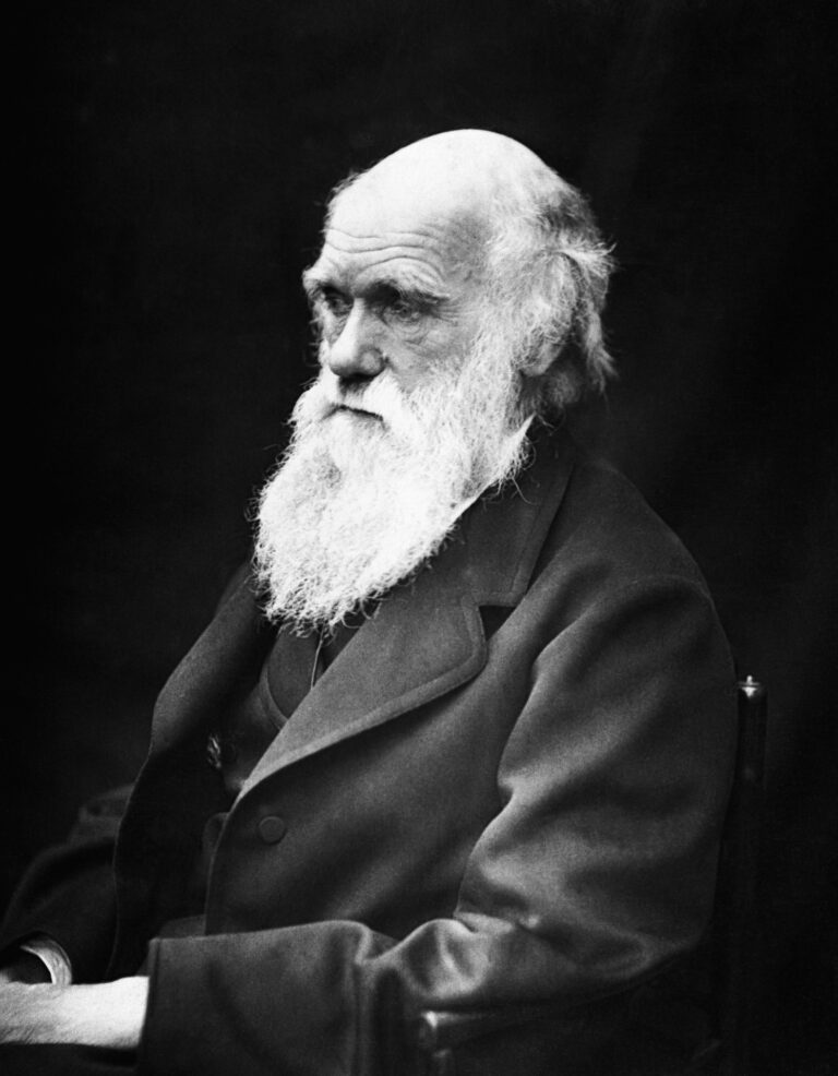 Charles Darwin, an elderly man with a long white beard, gazes thoughtfully to the side, highlighting his contemplative demeanor.