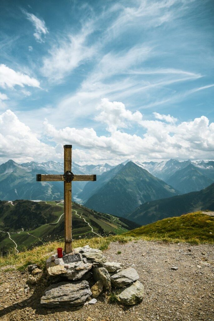 A cross on top of a hill with mountains in the background
